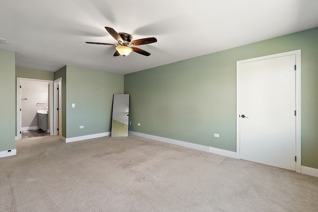 unfurnished bedroom with ceiling fan, ensuite bath, and light carpet