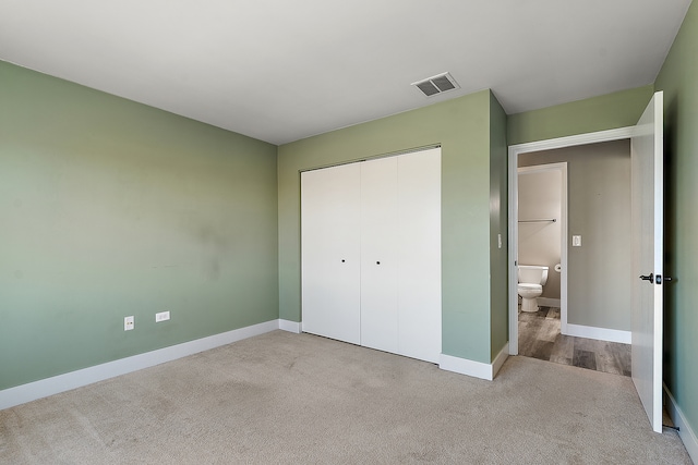 unfurnished bedroom with light colored carpet and a closet