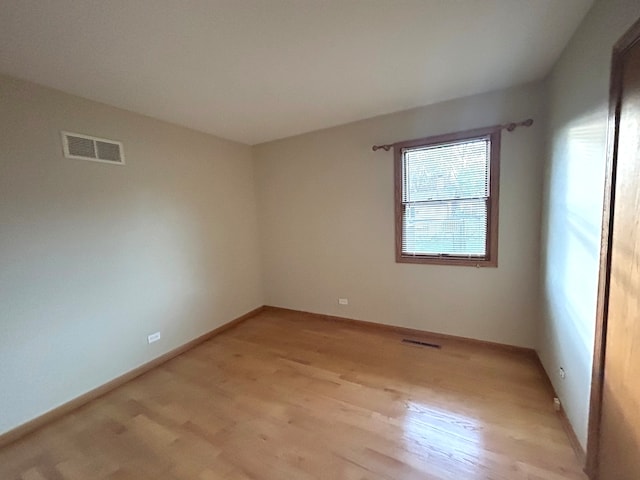 unfurnished room featuring light wood-type flooring and a notable chandelier