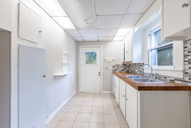 kitchen featuring white cabinetry, sink, decorative backsplash, and a drop ceiling