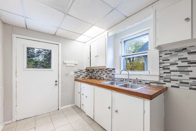 kitchen with white cabinets, butcher block counters, sink, and tasteful backsplash