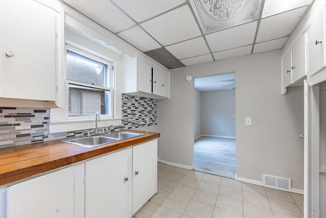 kitchen with backsplash, a drop ceiling, sink, and white cabinets