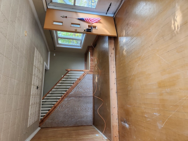 stairway with a skylight and wood finished floors