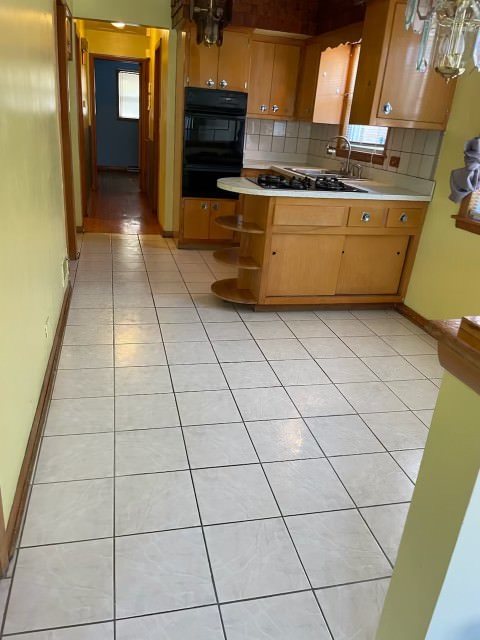 kitchen with double oven, decorative backsplash, and light tile patterned floors