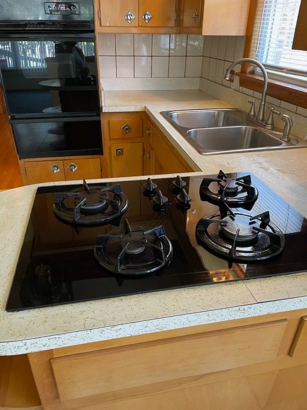 kitchen with decorative backsplash, sink, and black double oven