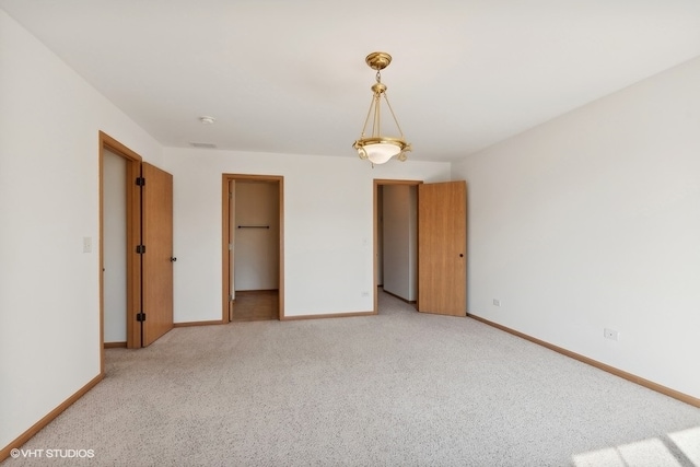 unfurnished bedroom with a walk in closet, light colored carpet, and a closet