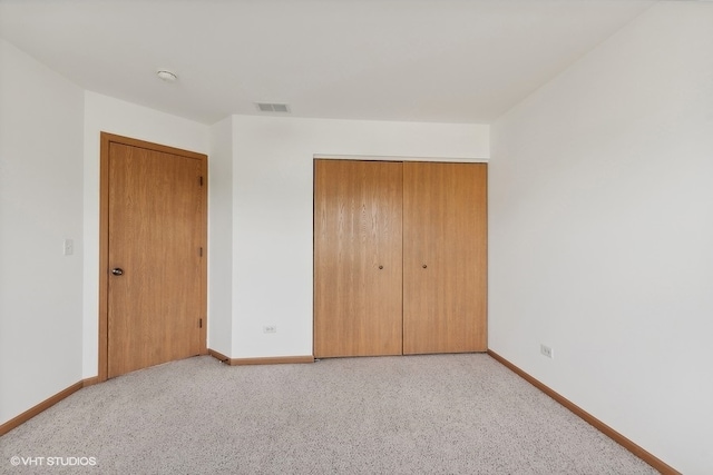 unfurnished bedroom with light carpet and a closet