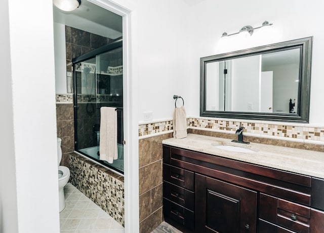 full bathroom featuring combined bath / shower with glass door, tile walls, toilet, vanity, and tile patterned floors