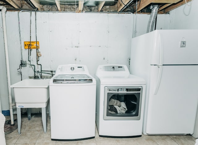 laundry room featuring washer and dryer, sink, and light tile patterned floors