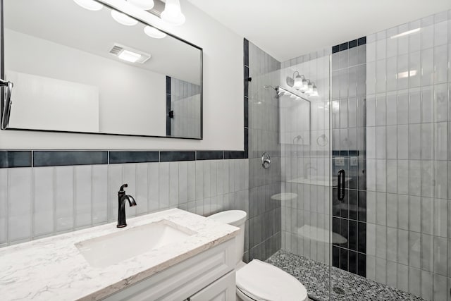 bathroom featuring toilet, walk in shower, vanity, and tile walls