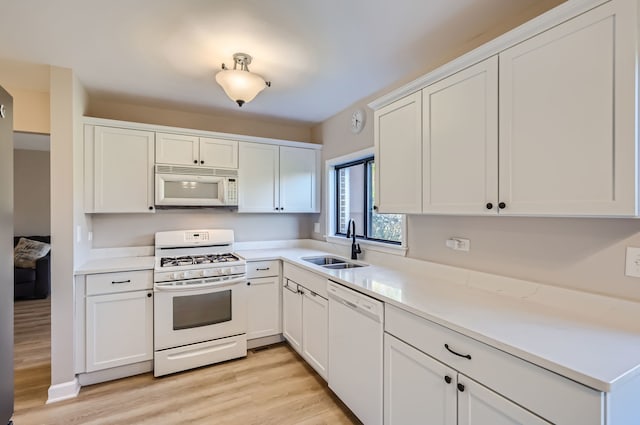 kitchen with light hardwood / wood-style flooring, white cabinetry, sink, and white appliances