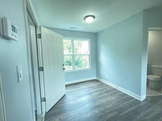 unfurnished bedroom featuring ensuite bath and dark hardwood / wood-style flooring