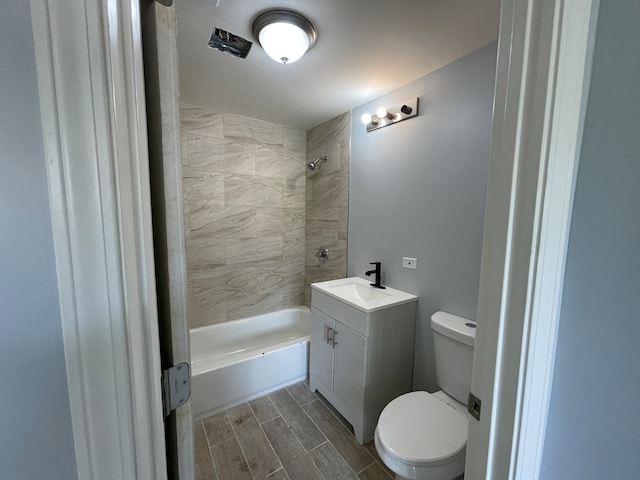 full bathroom with tiled shower / bath, vanity, and toilet