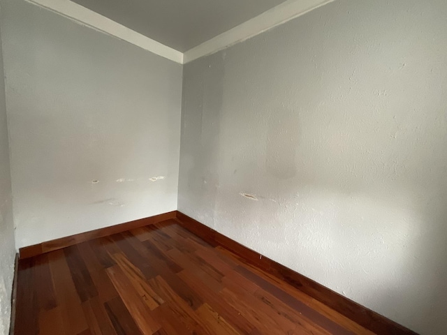 unfurnished room featuring ornamental molding and dark wood-type flooring