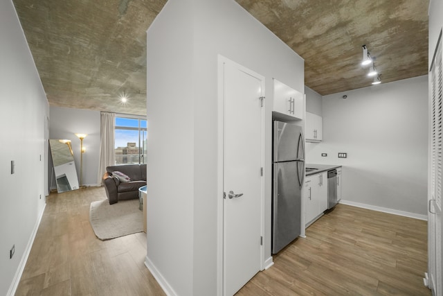 kitchen with appliances with stainless steel finishes, light wood-type flooring, and white cabinets