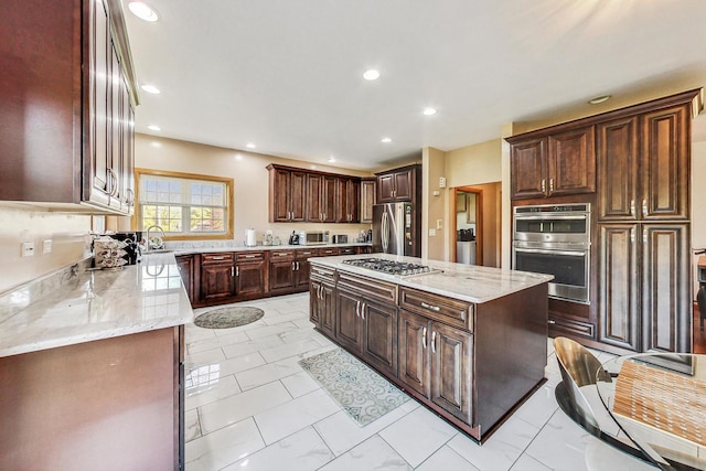 kitchen with sink, light stone counters, dark brown cabinets, a kitchen island, and appliances with stainless steel finishes