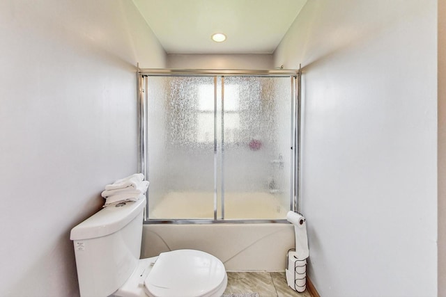 bathroom with bath / shower combo with glass door, tile patterned floors, and toilet
