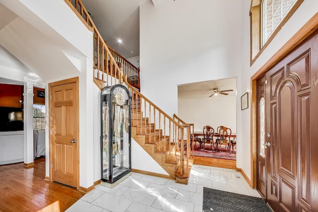 foyer entrance with a towering ceiling, ceiling fan, and a healthy amount of sunlight