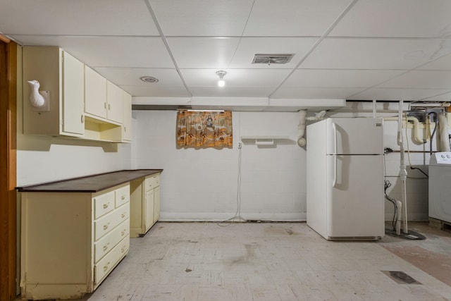 basement featuring a paneled ceiling, washer / clothes dryer, and white refrigerator