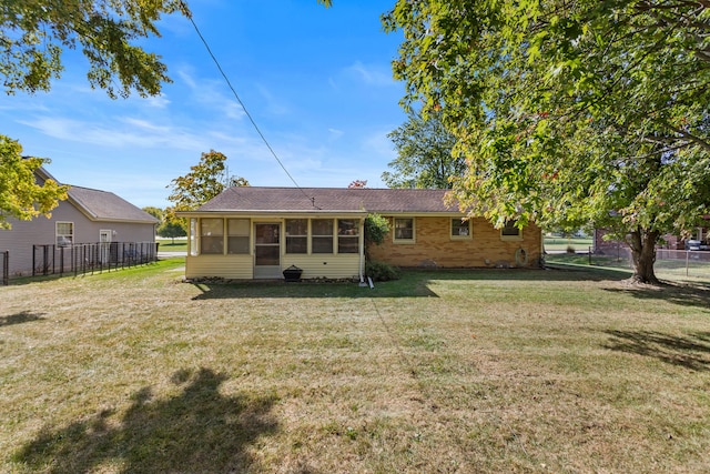 rear view of house featuring a sunroom and a lawn