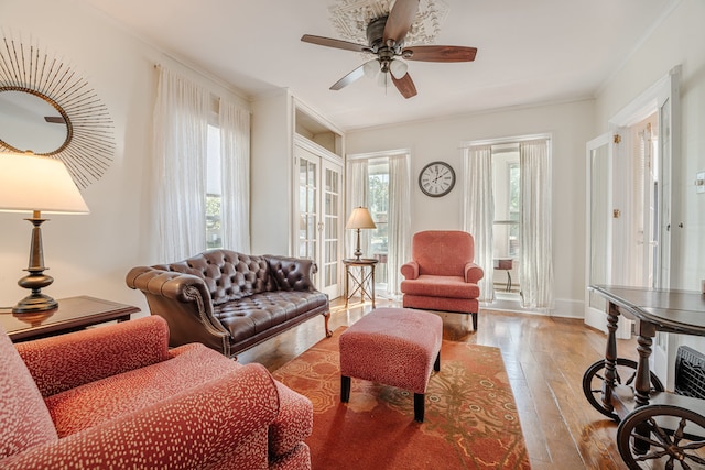 living room with ornamental molding, light hardwood / wood-style flooring, and ceiling fan