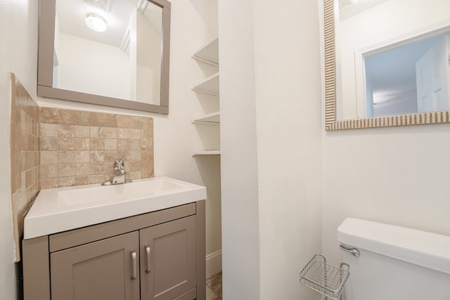 bathroom featuring vanity, toilet, and backsplash