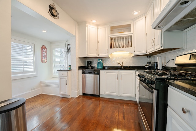 kitchen with appliances with stainless steel finishes, dark wood-type flooring, white cabinets, and exhaust hood