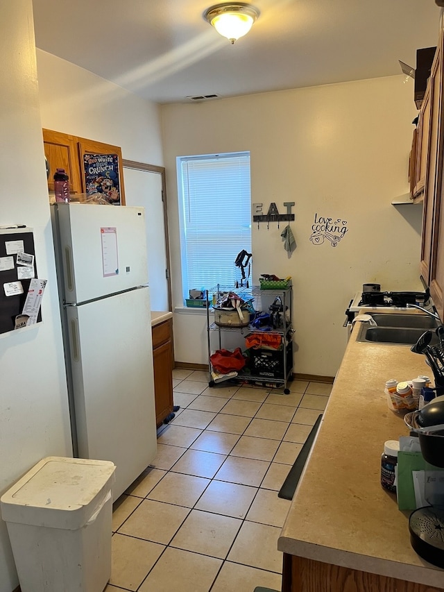 kitchen with light tile patterned flooring, sink, and white refrigerator