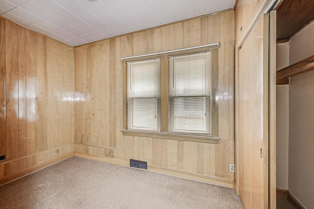 carpeted spare room with wooden walls