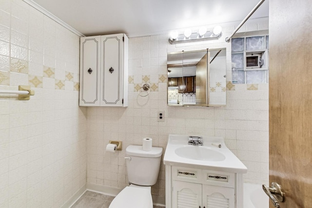 bathroom featuring tile patterned floors, vanity, toilet, and tile walls