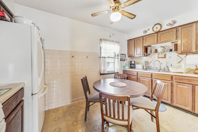 kitchen with ceiling fan, sink, tile walls, and white refrigerator