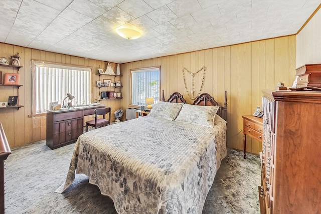 bedroom with carpet flooring, multiple windows, and wood walls