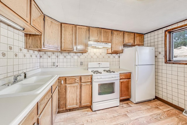 kitchen featuring backsplash, sink, light hardwood / wood-style floors, and white appliances