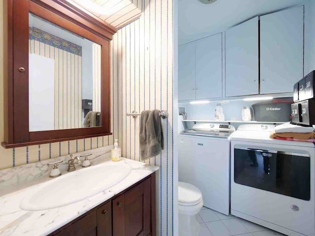 bathroom with tile patterned flooring, toilet, separate washer and dryer, and vanity