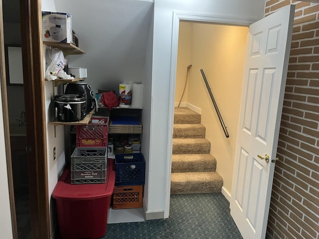 staircase featuring brick wall