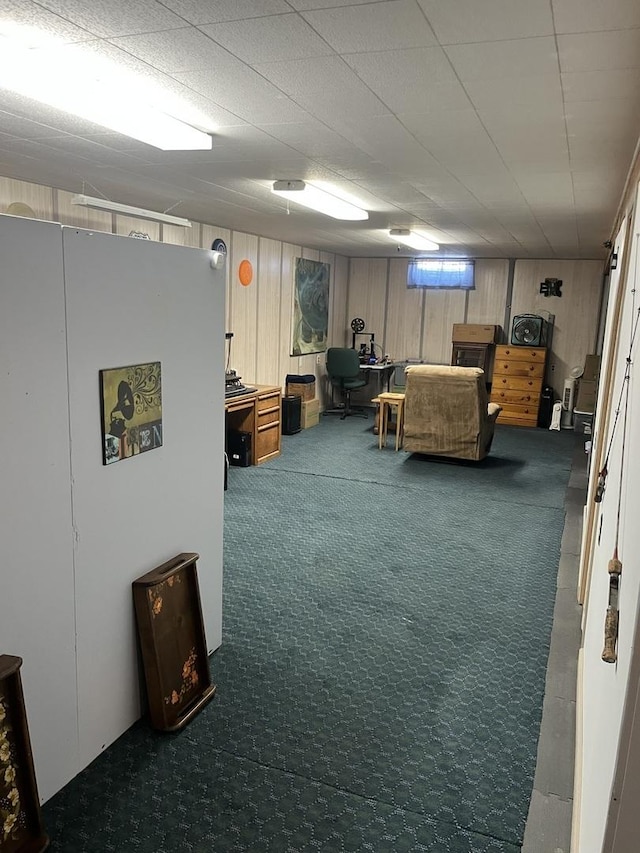 basement with dark carpet, wood walls, and white fridge