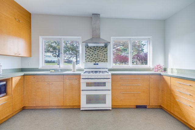 kitchen featuring plenty of natural light, wall chimney range hood, sink, and white range with gas stovetop