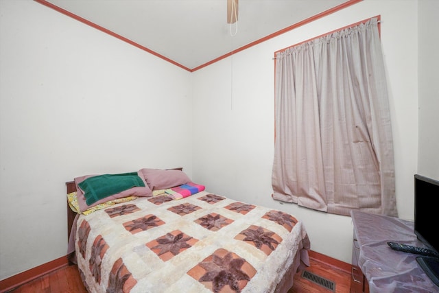 bedroom with ornamental molding, hardwood / wood-style flooring, and ceiling fan