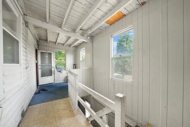 corridor featuring beam ceiling, wood walls, and wooden ceiling