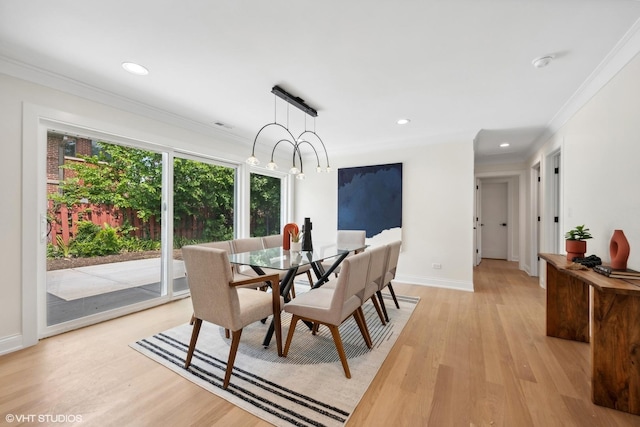 dining room with an inviting chandelier, ornamental molding, and light wood-type flooring