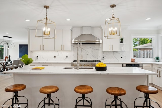 kitchen with a kitchen breakfast bar, a kitchen island with sink, and wall chimney range hood