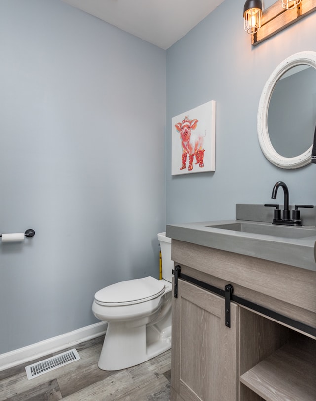 bathroom with toilet, hardwood / wood-style flooring, and vanity