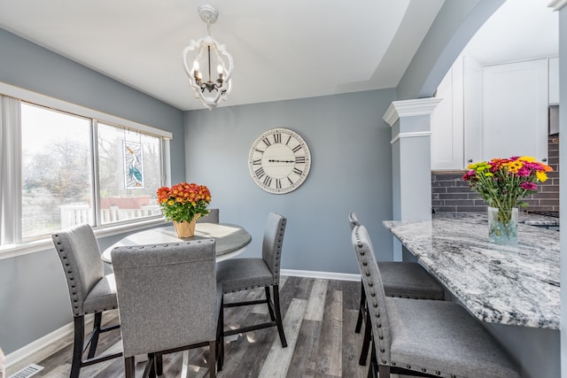 dining room featuring decorative columns, a chandelier, and dark hardwood / wood-style floors