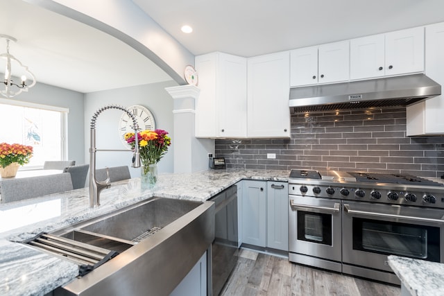 kitchen featuring decorative backsplash, white cabinets, appliances with stainless steel finishes, light hardwood / wood-style floors, and sink