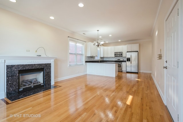 kitchen with ornamental molding, stainless steel appliances, decorative light fixtures, light hardwood / wood-style floors, and white cabinets