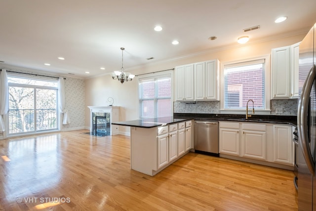 kitchen featuring pendant lighting, kitchen peninsula, white cabinetry, light wood-type flooring, and appliances with stainless steel finishes