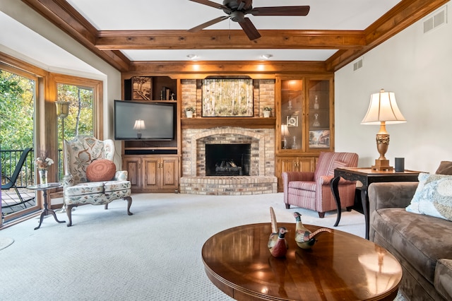 carpeted living room with beamed ceiling, ornamental molding, a fireplace, and ceiling fan