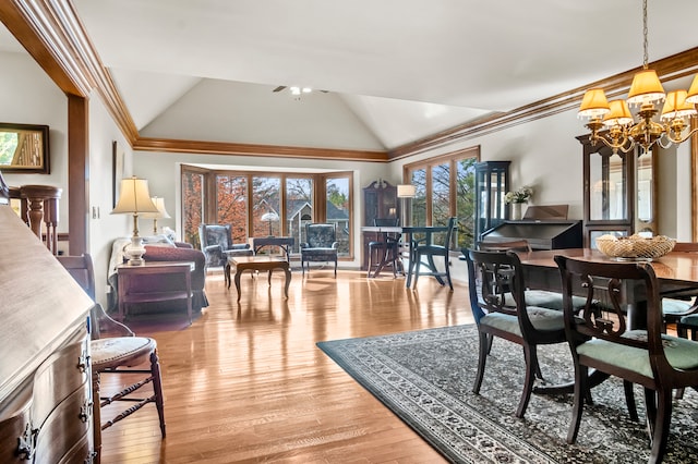 dining space featuring light hardwood / wood-style floors, ornamental molding, lofted ceiling, and a chandelier