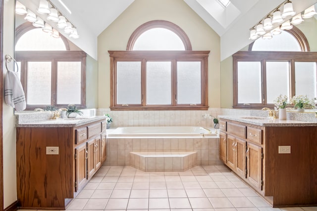 bathroom featuring vanity, a relaxing tiled tub, a skylight, and plenty of natural light