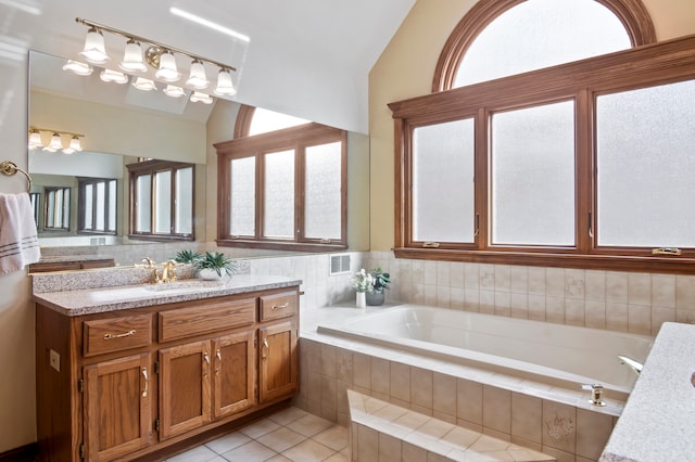 bathroom with vanity, lofted ceiling, tile patterned floors, and tiled bath